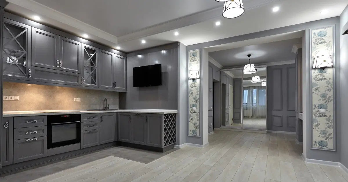 A modern kitchen with laminated floors, grey drawers, black appliances, and multiple lamps, next to a hallway.