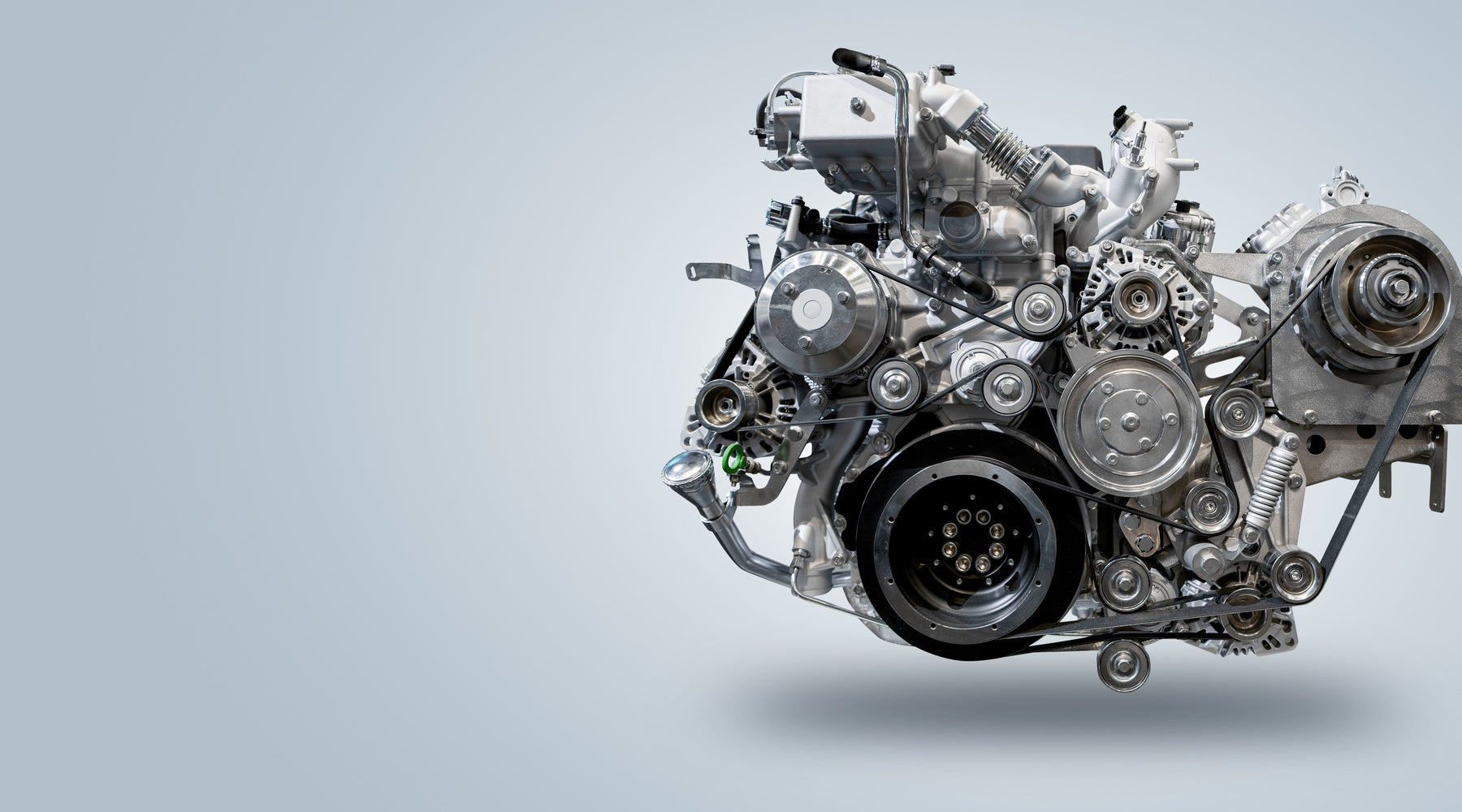 A modern diesel truck engine, with visible turbocharger, pulleys, and belts, isolated to the right on a light gray background.