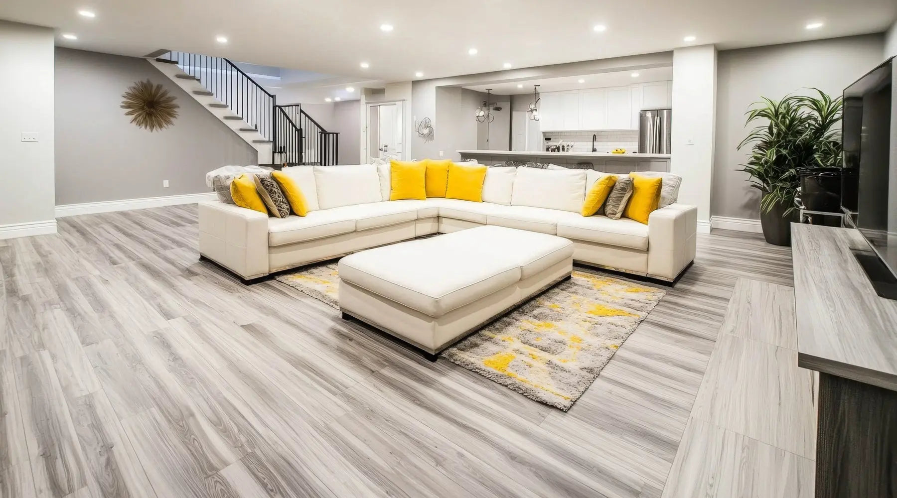 A large, comfortable basement with gray walls and floors, a white sectional, and gray and yellow pillows.