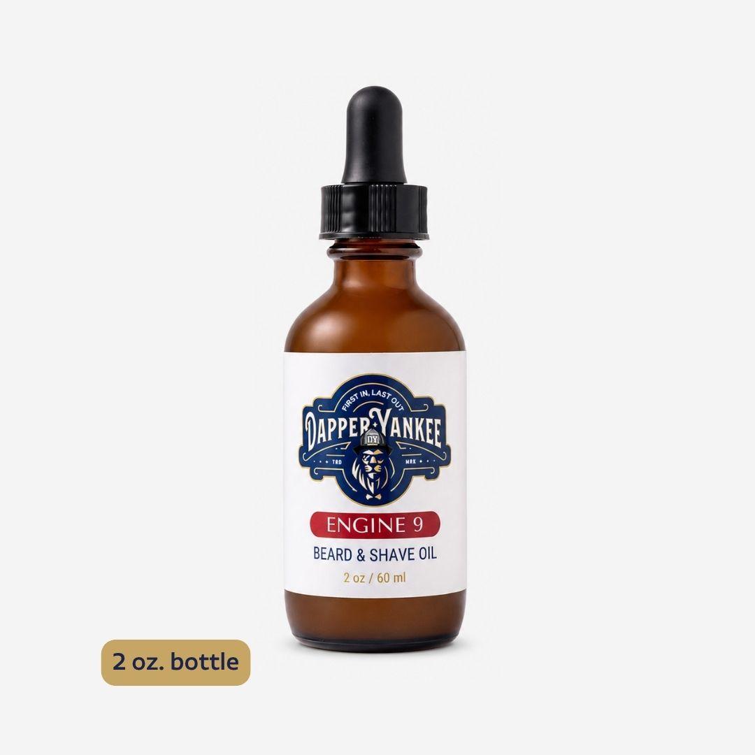 A 2 oz amber glass dropper bottle of Dapper Yankee Engine 9 Beard & Shave Oil, shown on a light gray background with a small '2 oz. bottle' label overlay in the bottom left corner.