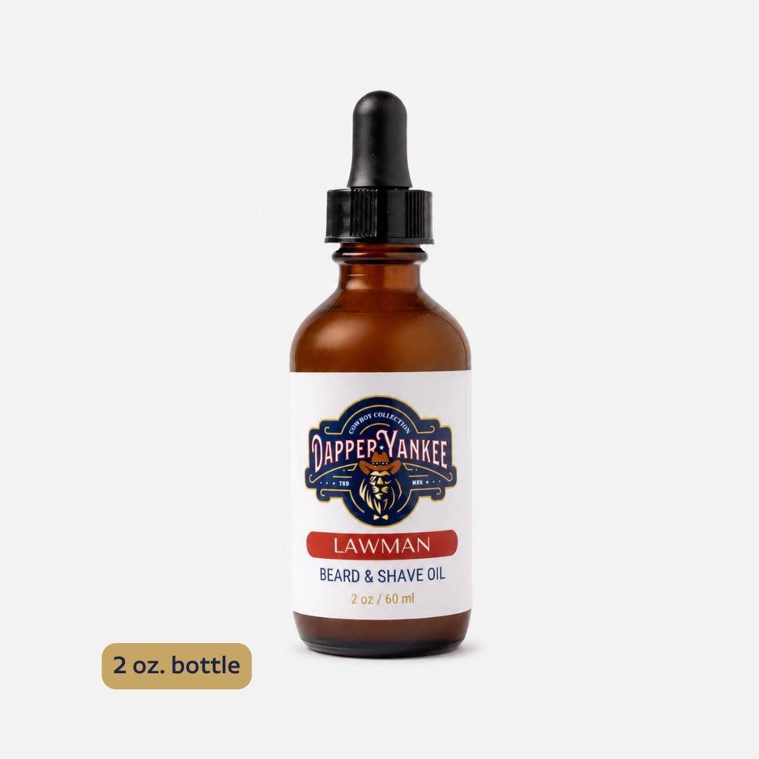 An amber glass dropper bottle of Dapper Yankee Lawman Beard & Shave Oil on a light gray background, with a gold '2 oz. bottle' label overlay in the bottom left corner.