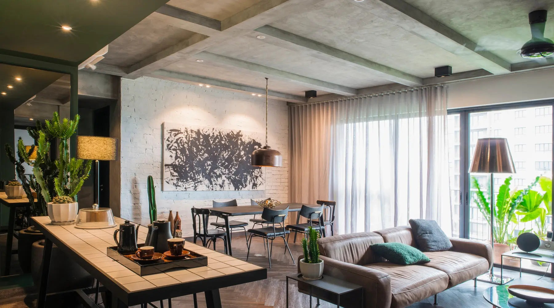 The interior of an apartment with an open-floor layout, modern furniture, cream brick walls, and modern art on the walls.