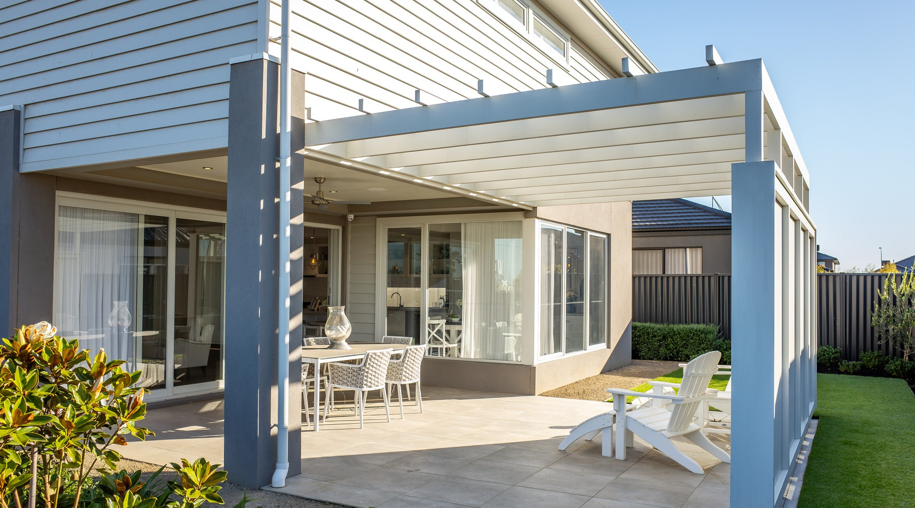 A home with white siding with an attached patio with a pergola and outdoor furniture set up underneath.