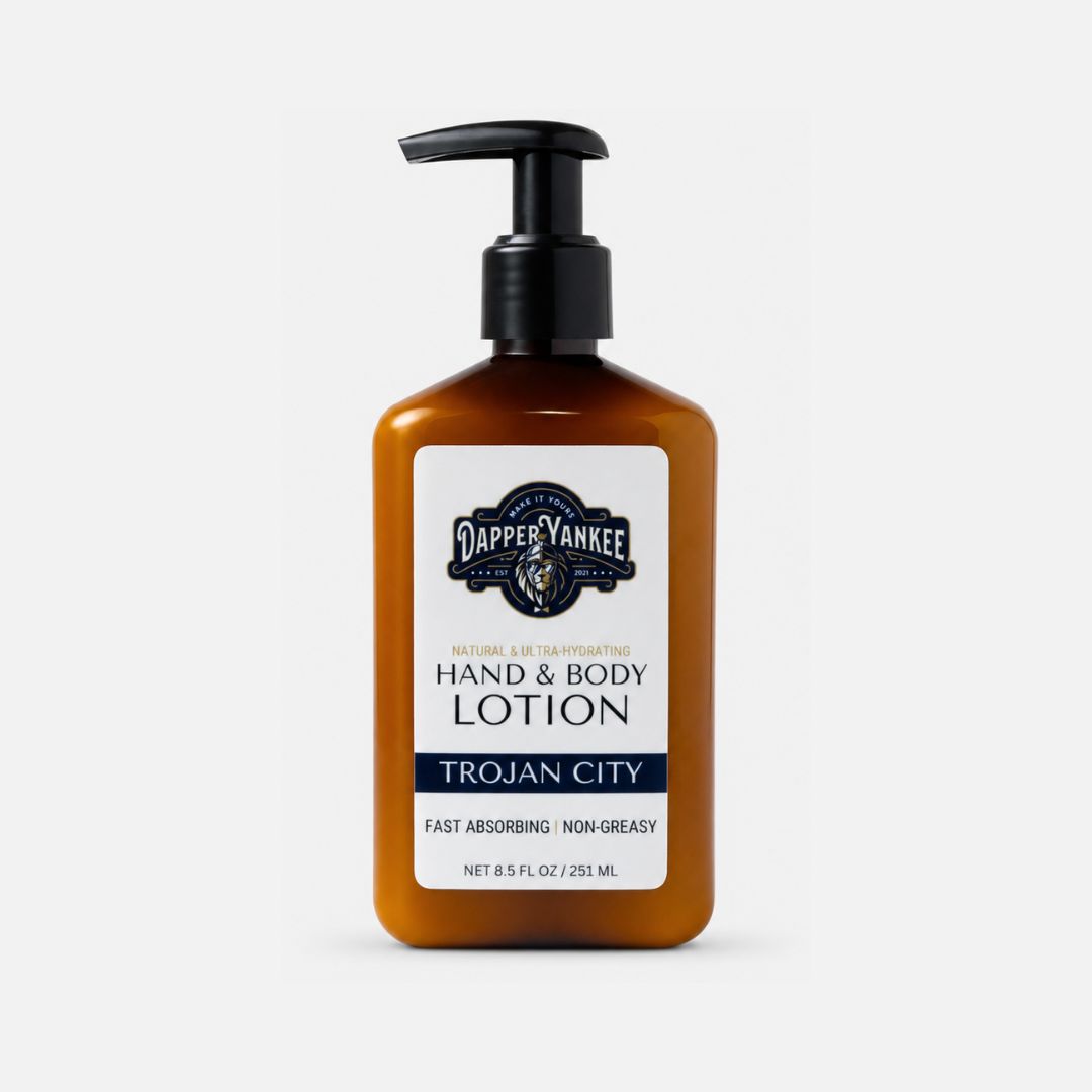 A bottle of Dapper Yankee Trojan City Hand & Body Lotion in an amber brown bottle with a black pump dispenser and a white label, set against a light gray background.
