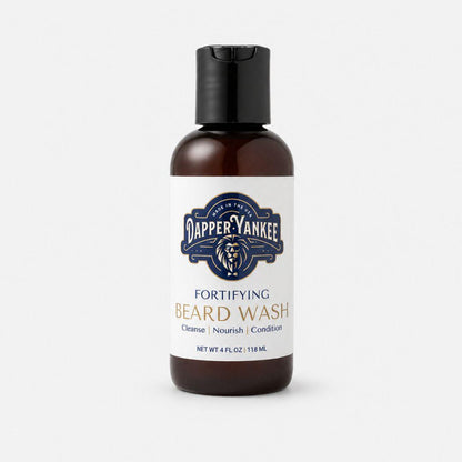 A 4 fl oz amber bottle of Dapper Yankee Fortifying Beard Wash with a black flip-top cap and a white label, set against a light gray background.