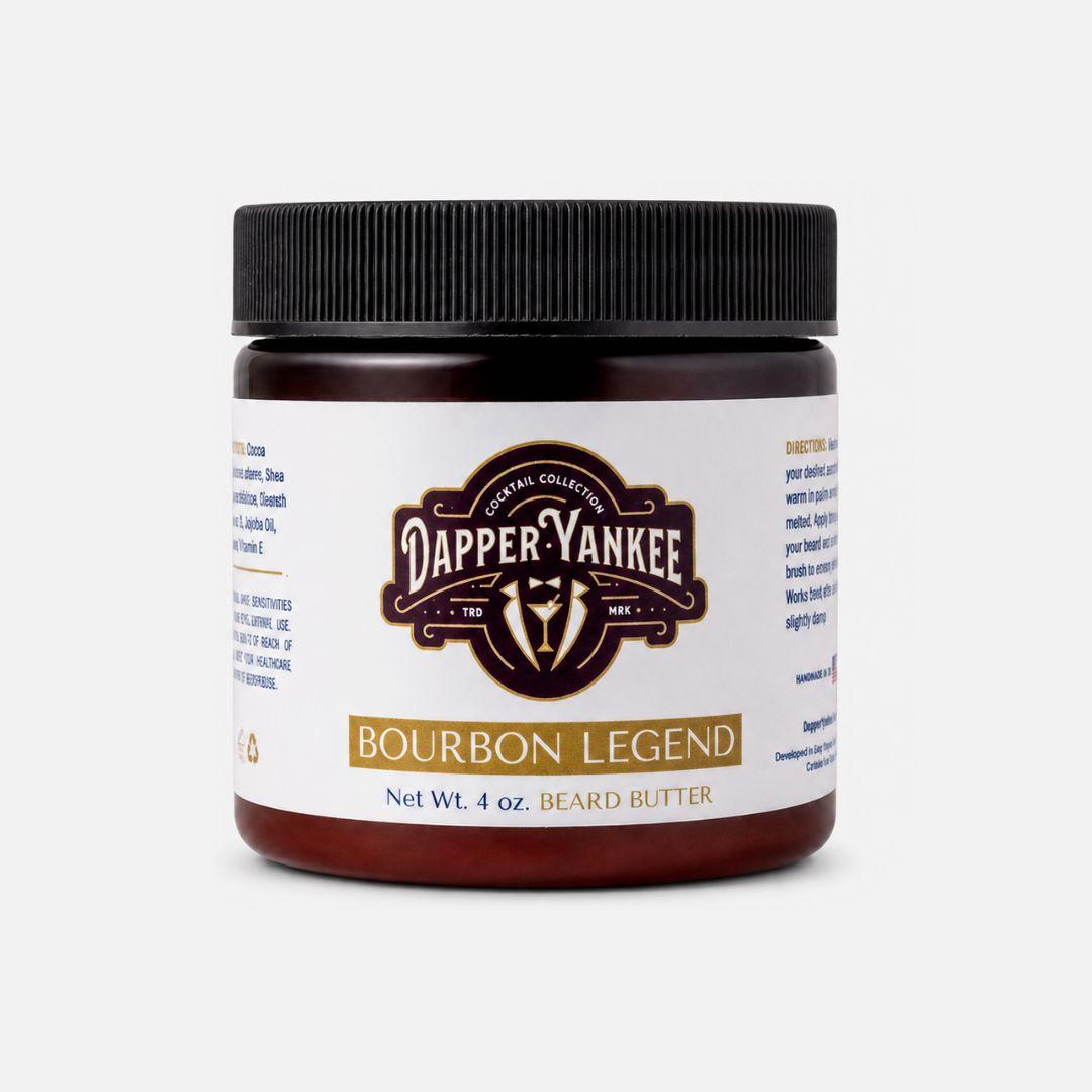 A 4 oz jar of Dapper Yankee Bourbon Legend beard butter, featuring a dark amber container, a black ribbed lid, and a white label with gold and dark brown accents.
