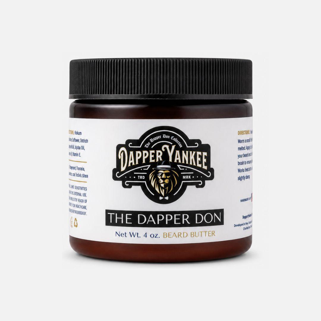A 4 oz jar of Dapper Yankee The Dapper Don Beard Butter on a light gray background. The product is in a dark amber jar with a black ribbed screw cap and a white label featuring the brand logo and product name.