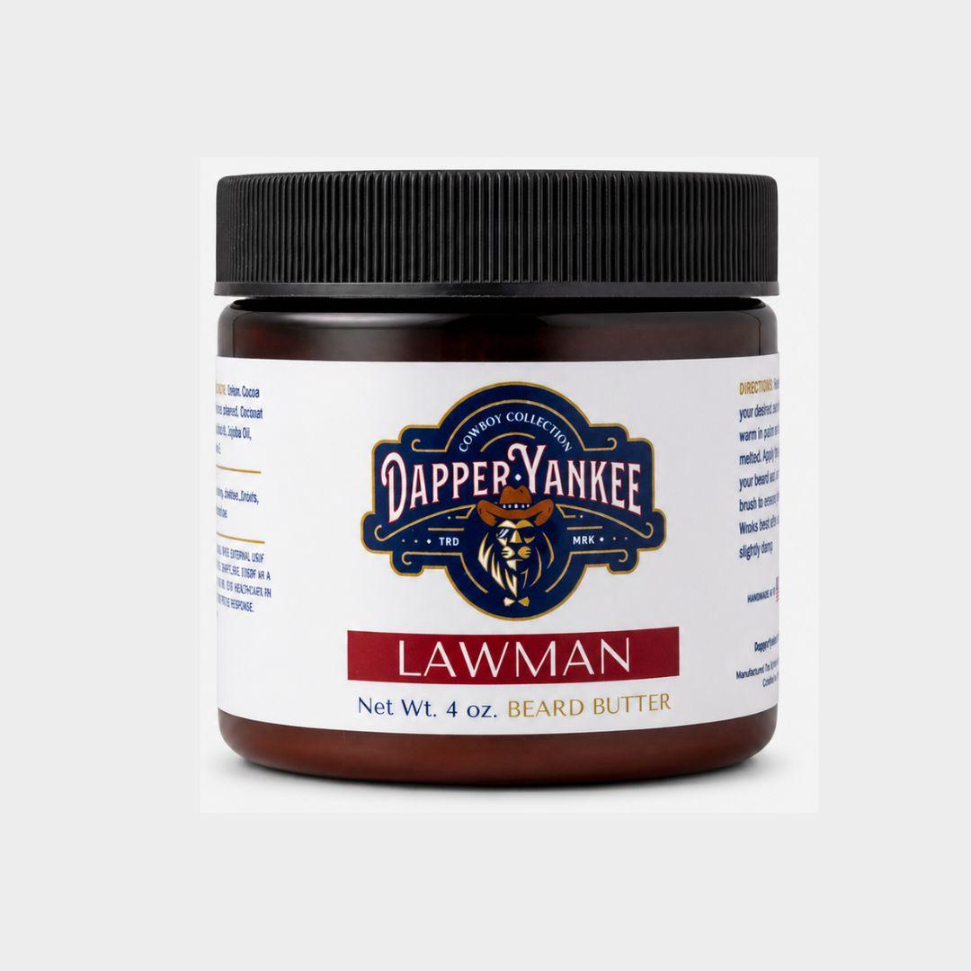 A 4 oz jar of Dapper Yankee Lawman beard butter, featuring a dark amber container, a black ribbed lid, and a white label with navy and red branding.