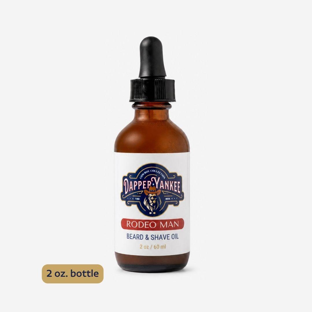 An amber glass dropper bottle of Dapper Yankee Rodeo Man Beard & Shave Oil on a light gray background, with a small '2 oz. bottle' label overlay in the bottom left corner.