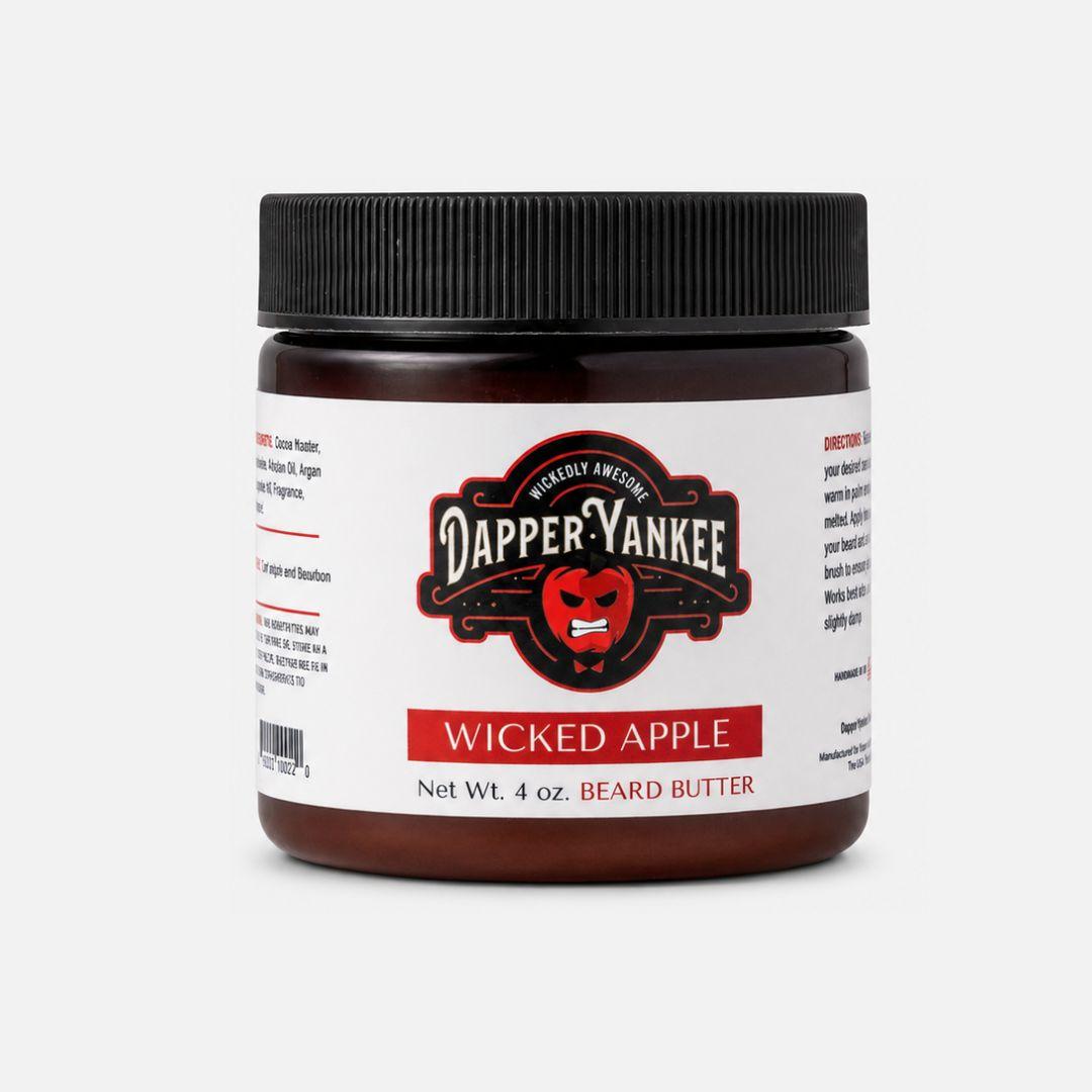 A 4 oz jar of Dapper Yankee Wicked Apple Beard Butter on a light gray background. The product features a dark amber jar, a black ribbed screw cap, and a white label with red and black text and logo.