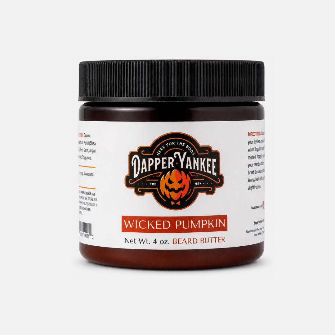 A 4 oz jar of Dapper Yankee Wicked Pumpkin beard butter, featuring a white label with a black and orange pumpkin logo and a black ribbed screw cap, set against a light gray background.